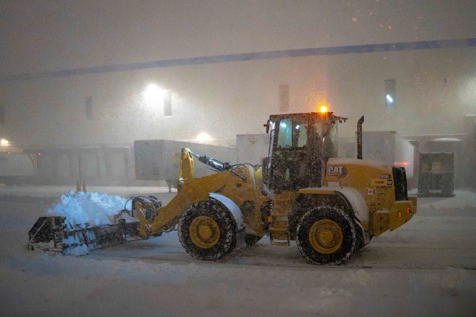 Spartan loader clearing heavy snow at night under equipment lighting