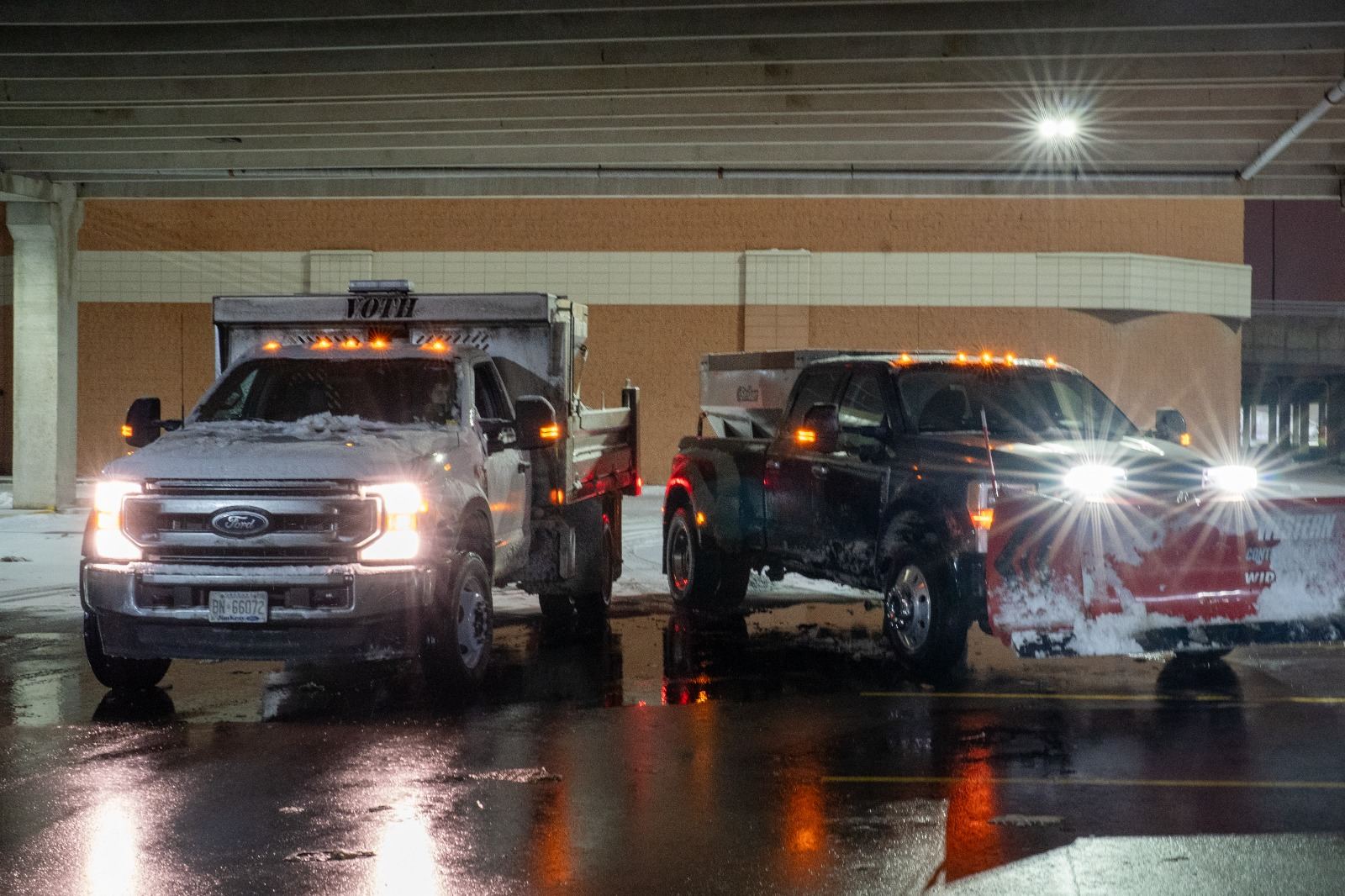 Snow removal trucks with salt spreaders working in parking garage during storm